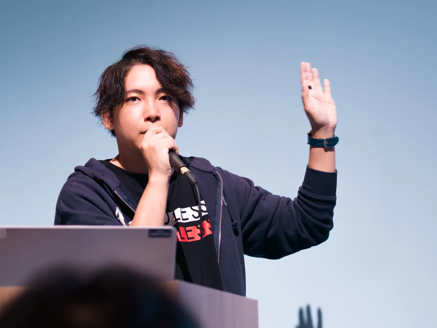 ステージで手を挙げながらマイクで話すメンバー